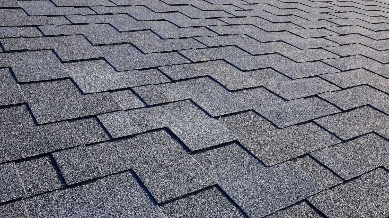 Close view of dark gray asphalt shingles in a staggered pattern